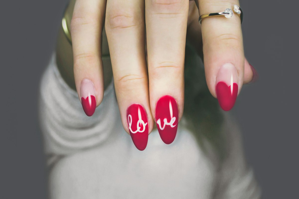 A red custom nail art set with hand-lettered detail