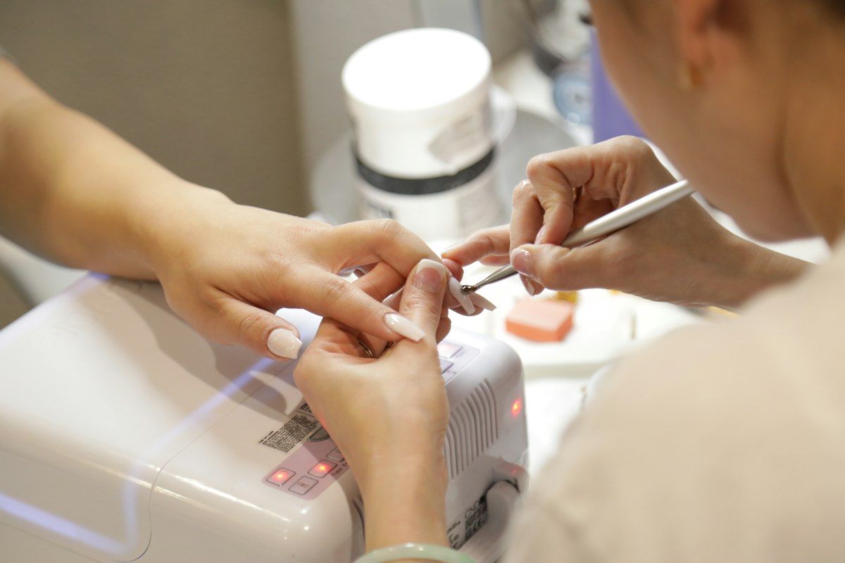 A nail artist applying extensions at the studio table