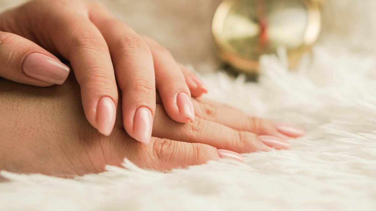 A fresh blush pink manicure resting on soft white