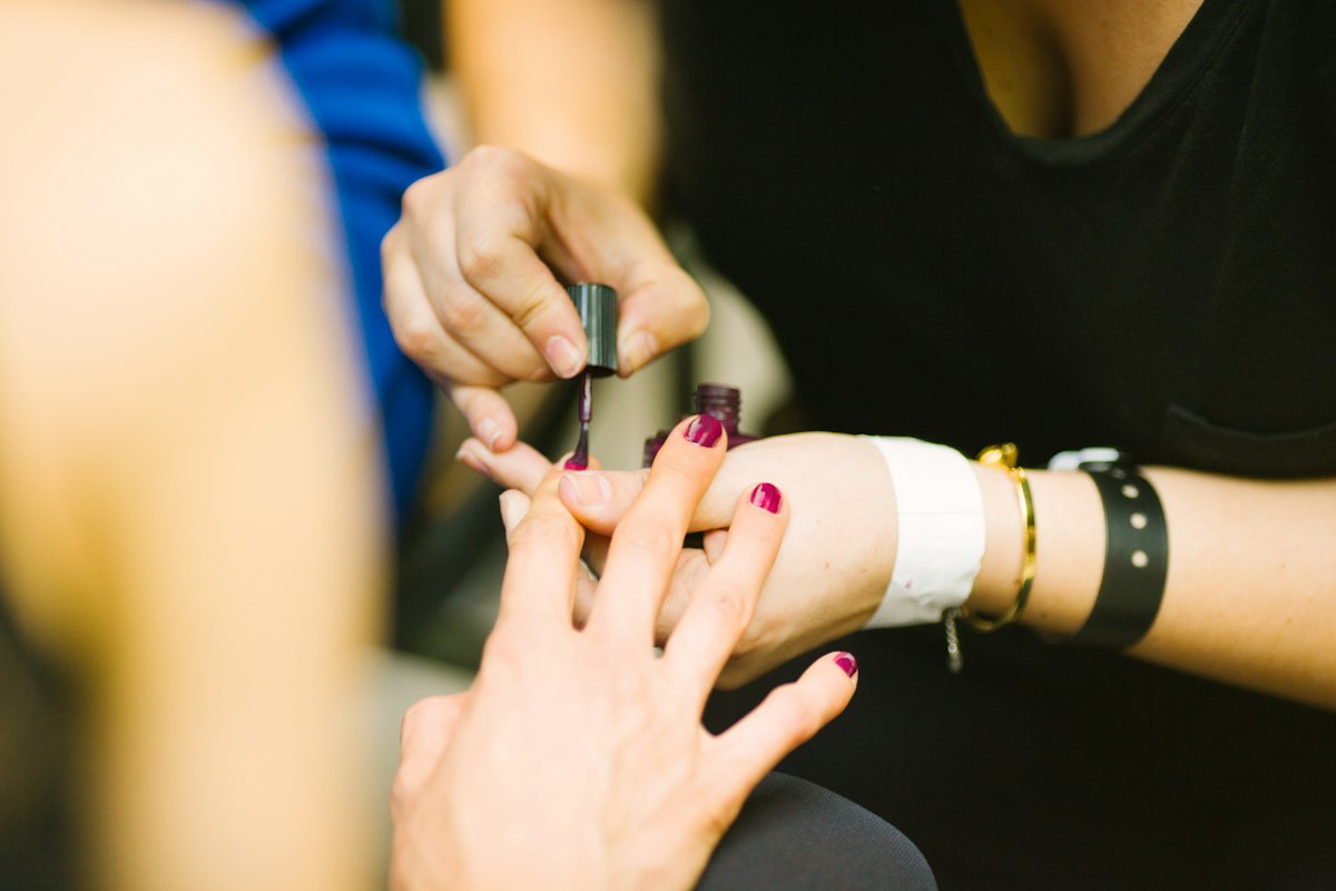 Deep berry gel polish being applied during a manicure